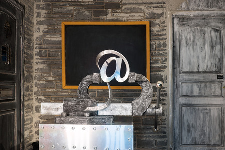 Sign of e-mail in grip on a background of blackboardの写真素材