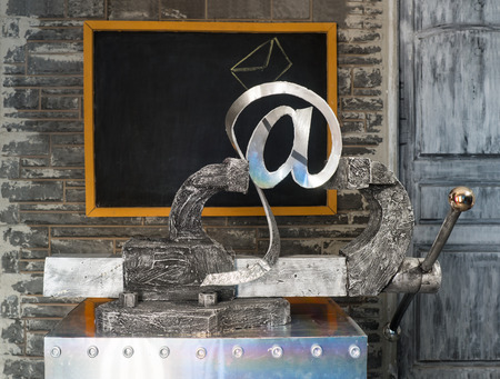 Sign of e-mail in grip on a background of blackboardの写真素材