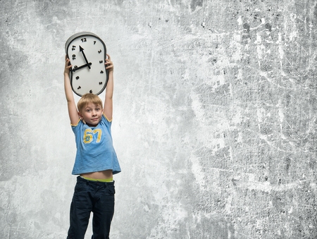 Boy holding a clock in his handsの写真素材