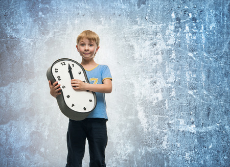 Boy holding a clock in his handsの写真素材