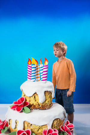 Boy blows out the candles on the cakeの写真素材