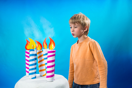 Boy blows out the candles on the cakeの写真素材
