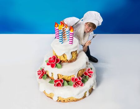 Cheerful confectioner cuts a birthday cake