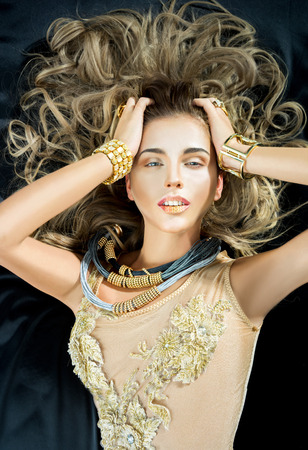 Sexy blonde woman in gold lingerie lying in the bedの写真素材