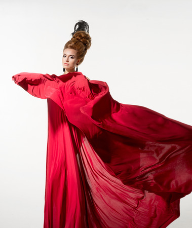 Beautiful woman in a silk red fabric on the white backgroundの写真素材