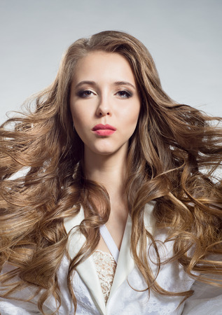 Portrait of a beautiful woman with a flowing hair in a white negligeeの写真素材