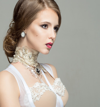 Portrait of a sexy woman with brown hair in a white lingerie on a gray backgroundの写真素材