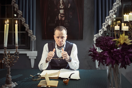 Imposing man is working creatively at the table with candlesの写真素材