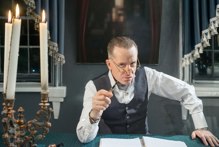 Serious businessman sitting at the table with pens in handの写真素材