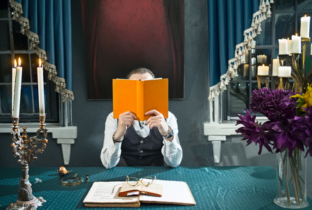 Man with a book in hands at the table in his studyの写真素材