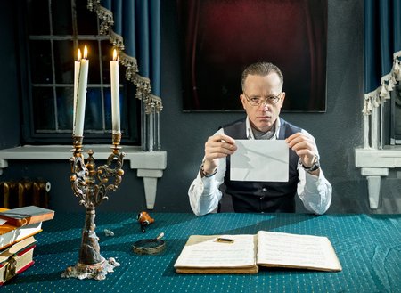 Man with a book in hands at the table in his studyの写真素材