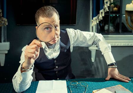 Elegant man looking through a magnifying glassの写真素材