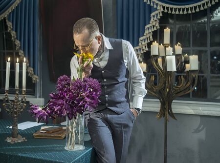 Businessman sniffing a bouquet of flowers in vase on the tableの写真素材