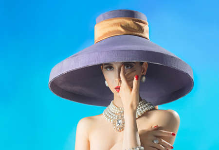 Portrait beautiful woman in the lilac hat with a hand near faceの写真素材
