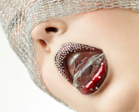 Crystal is in the mouth of the beautiful woman with a red lipsの写真素材