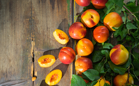 Beautiful peaches  and slices of peach on the old wooden boardsの写真素材