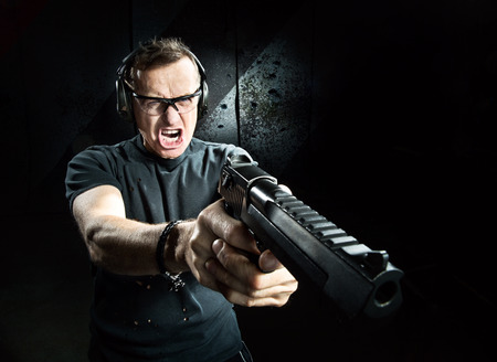 Gun in the hands of the angry man in a headphones の写真素材