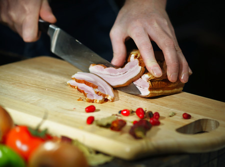 Chef cuts the smoked meat knife on a cutting boardの写真素材