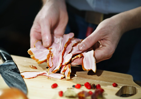 Chef with appetizing pieces of the bacon in their hands