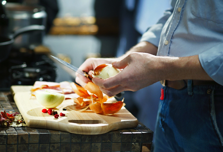 Man cleans the onion with a kitchen knife in the kitchenの写真素材