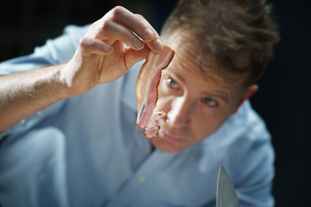 Chef with pieces of the bacon in their handの写真素材