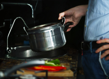 Man pours into the pan water from the tap の写真素材