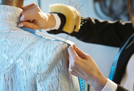 Couturier sews a dress in the studio