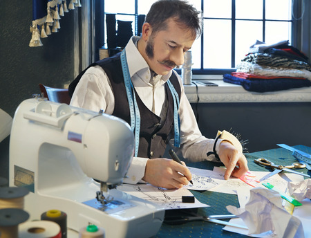 Designer is working at his desk over a sketch of clothesの写真素材