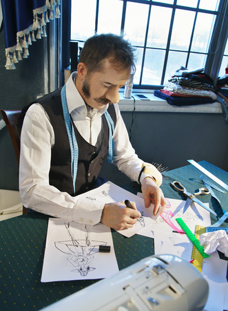 Designer is working at his desk over a sketch of clothesの写真素材