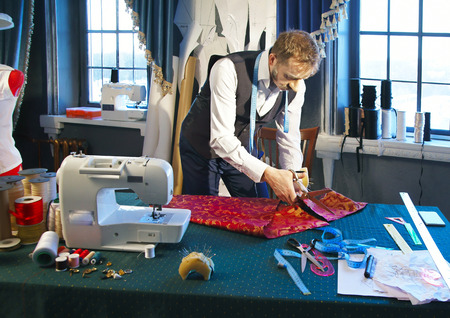 Designer cuts out a dress from red fabric の写真素材