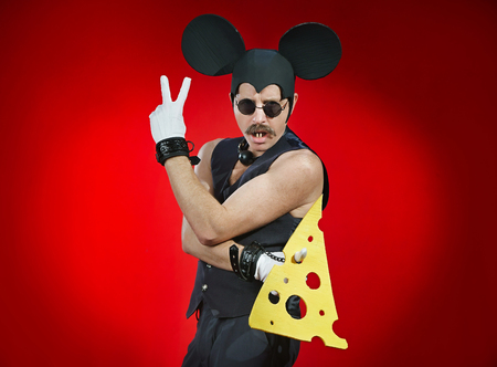 Man in a costume of a mouse with a piece of cheese in his handsの写真素材