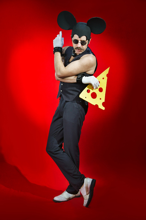 Man in a costume of a mouse with a piece of cheese in his handsの写真素材