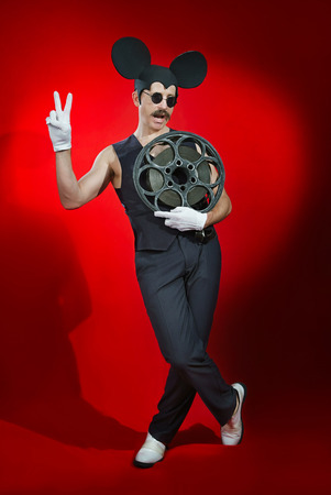 Man in a hat of a mouse with a reel of filmの写真素材