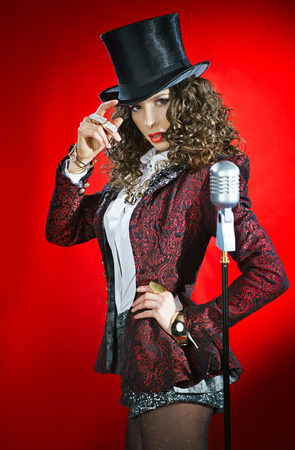 Beautiful woman singer with microphone on the red backgroundの写真素材