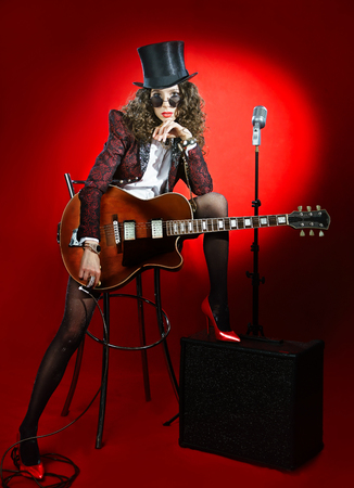 Attractive girl musician in hat with guitar and microphoneの写真素材