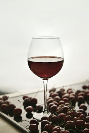 Ripe cherries and a glass with a cherry drink on a tableの写真素材