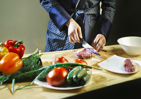 Man cuts the meat with a knife on a kitchenの写真素材