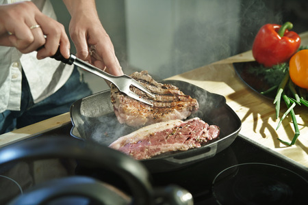 Cook fries pieces of meat in a flying panの写真素材