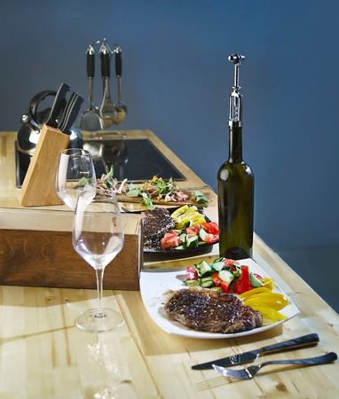 Roast meat steak in a plate with vegetables and wine bottleの写真素材