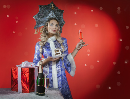 Beautiful snow maiden with a piece of cake, gift and champagneの写真素材