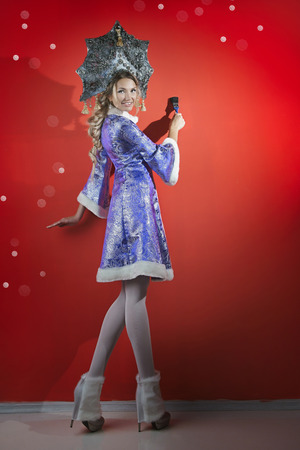 Cheerful Snow Maiden with a brush in his hand near a red wallの写真素材