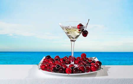 Glass of wine and cherries on a background seascapeの写真素材