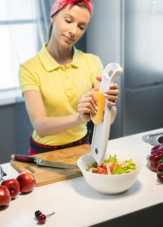 Woman preparing salad with cheese in the kitchenの写真素材