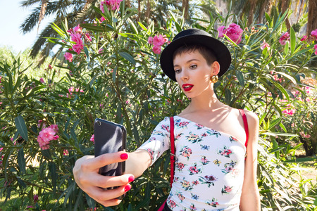 Tourism in Europe, woman taking selfie self-portrait on smartphone on flowers backgroundの写真素材