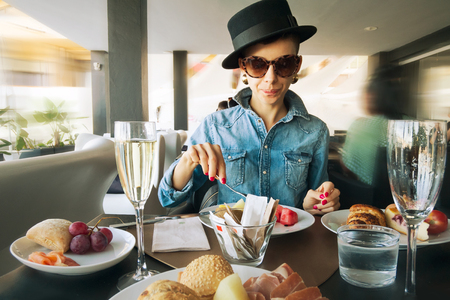 Young woman sitting at table in restaurant and eating dessertの写真素材