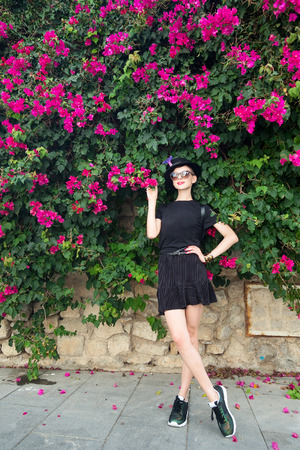 Slim girl outdoors surrounded by flowering plantsの写真素材