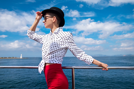 Woman in black hat and white blouse on yacht enjoying sea walkの写真素材