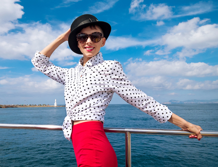 Woman in black hat and white blouse on yacht enjoying sea walkの写真素材