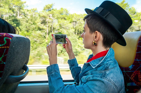 Young woman with mobile phone on the bus near the windowの写真素材