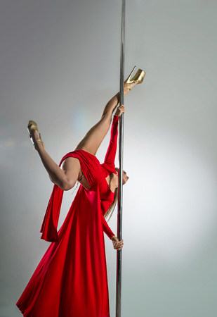Slim sexy woman in a red dress dancing on a pylonの写真素材